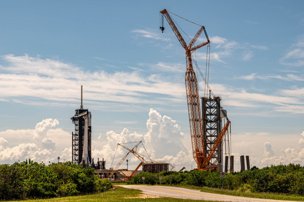 A wide view of 39A from the east looking west to with clouds backdropping construction of SpaceX's Starship/ Superheavy pad adjacent from where Falcon 9 & Dragon currently launch.