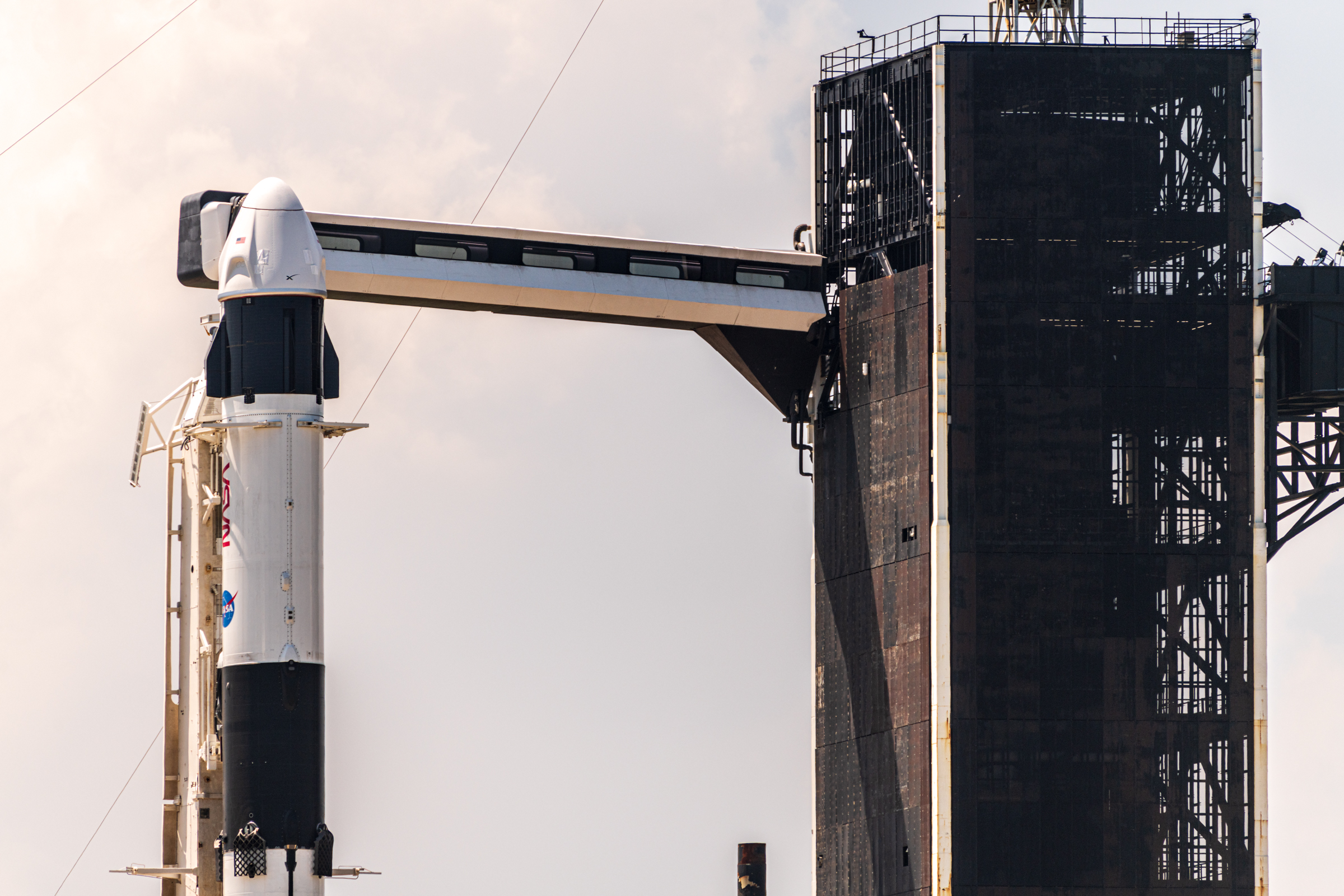 A closer view from cape Rd. The upper-stage and spacecraft, crew access arm and tower. The black paneling on the outside of the tall gantry structure is beginning to show signs of rust.