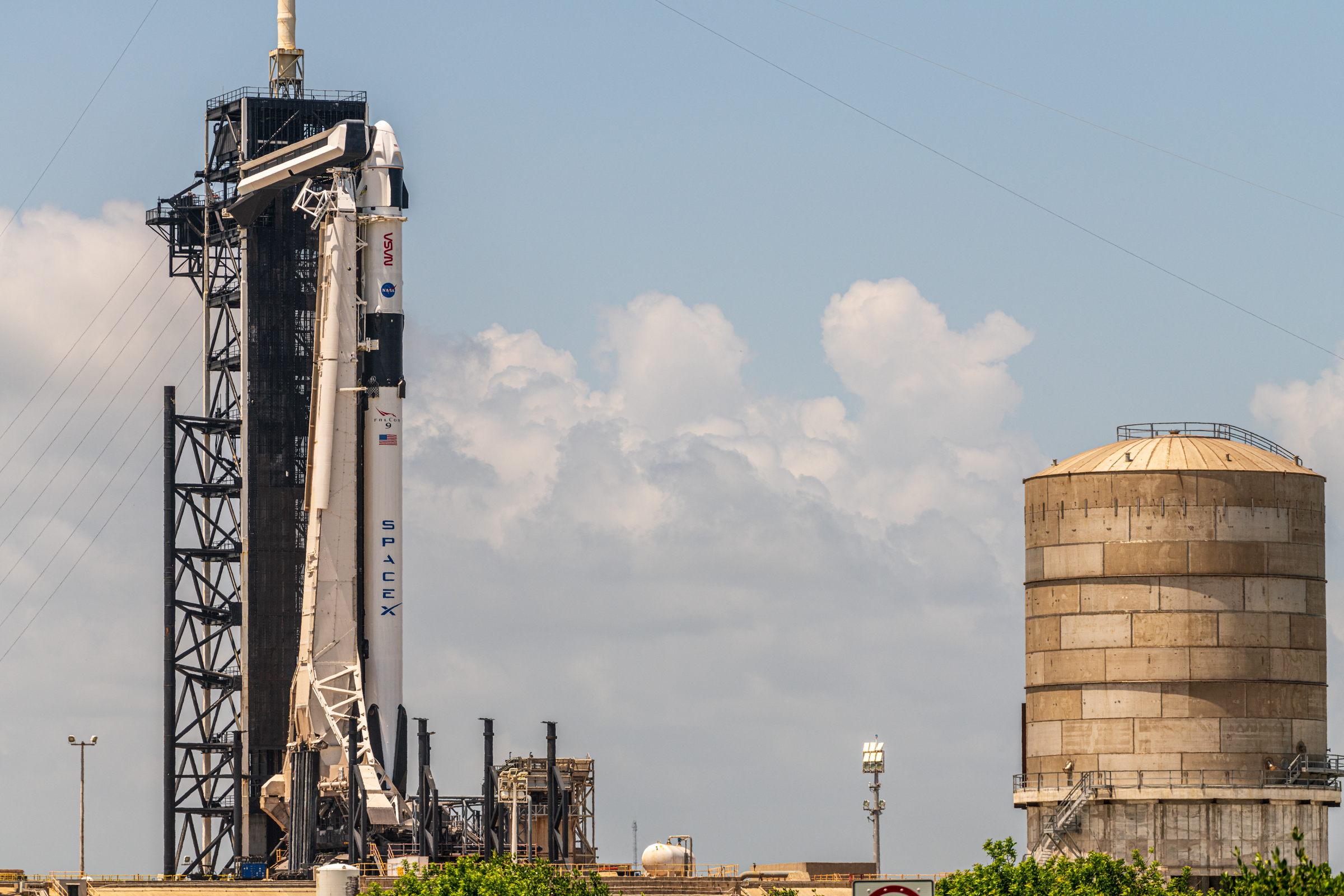 Wider view just east of 39A with Falcon 9 standing vertical and a water tank for Starship.